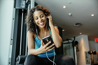 Woman listening to earbuds in gymnasium