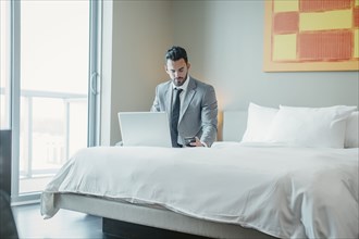 Businessman using laptop on hotel bed