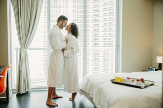 Couple hugging in bathrobes in hotel room