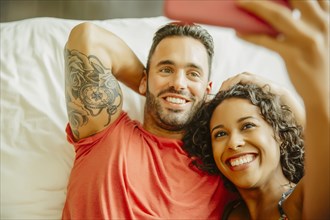 Couple taking selfie with cell phone on bed