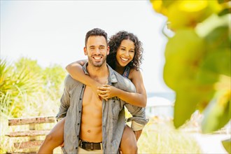 Man carrying girlfriend piggyback on beach