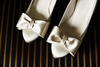 Close up of white high heels with bows
