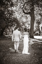 Caucasian bride and groom walking on dirt path