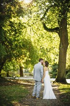 Caucasian bride and groom kissing on dirt path
