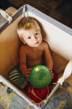 Mixed race boy playing in laundry hamper