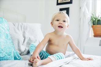 Mixed race boy sitting on bed