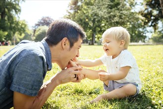 Father and son playing in grass in park