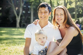 Smiling family sitting on grass in park