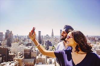 Indian couple taking selfie over New York cityscape