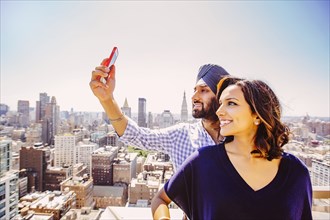 Indian couple taking selfie over New York cityscape