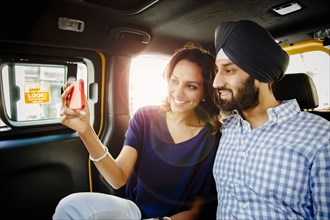 Indian couple taking selfie with cell phone in taxi