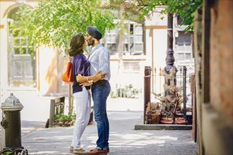 Indian couple kissing on city sidewalk