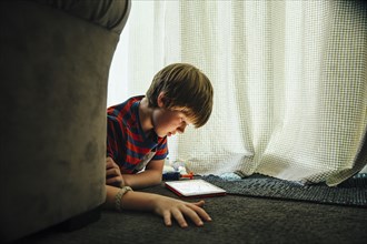 Caucasian boy using digital tablet in blanket fort