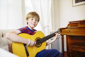 Caucasian boy playing guitar in living room
