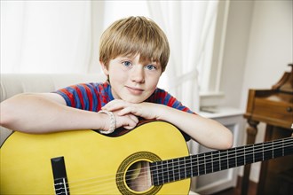 Caucasian boy holding guitar in living room