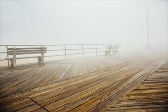 Fog over benches on wooden boardwalk