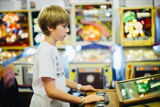 Caucasian boy playing video game in arcade