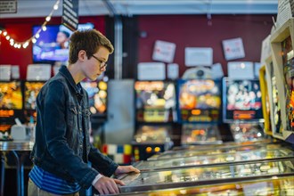 Caucasian teenage boy playing video game in arcade