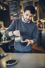 Caucasian barista making coffee in cafe