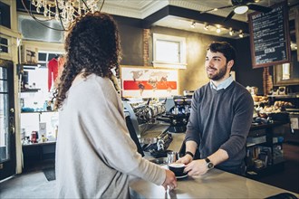 Barista serving customer coffee in cafe