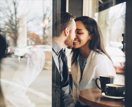 Smiling couple kissing in cafe
