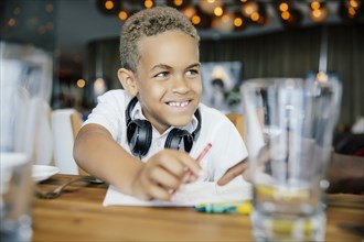 Mixed race boy coloring at restaurant table