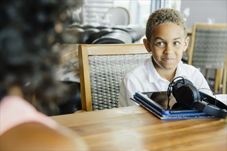 Boy with digital tablet sitting at restaurant
