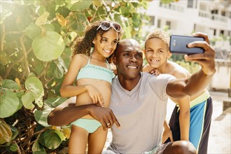 Father and children taking selfie with cell phone outdoors