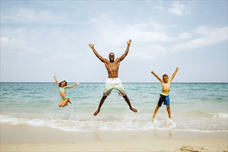 Father and children jumping for joy on beach