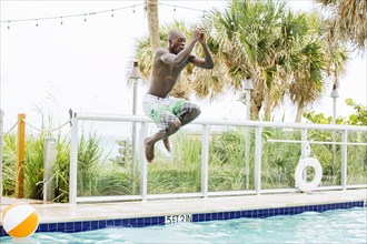 Black man jumping into swimming pool