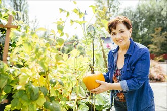 Caucasian woman holding pumpkin in garden