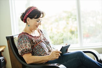 Caucasian woman using digital tablet in armchair