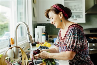 Caucasian woman washing vegetables in kitchen