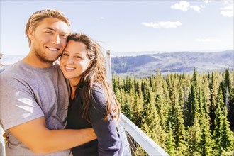 Caucasian couple hugging over forest treetops