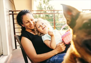 Caucasian mother and daughter playing with dog on patio