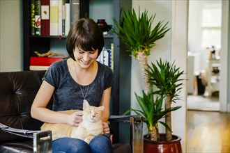 Caucasian woman petting cat in living room