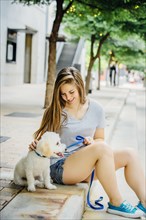 Caucasian woman petting dog on sidewalk