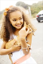 Mixed race girl petting dog outdoors
