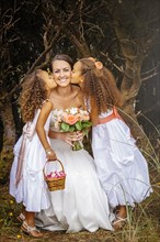 Flower girls kissing bride outdoors