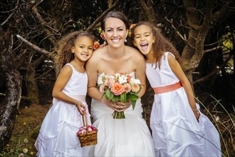 Flower girls smiling with bride outdoors