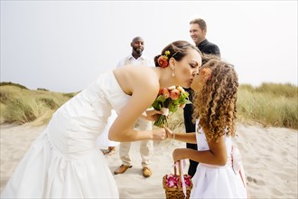 Flower girl kissing bride in wedding