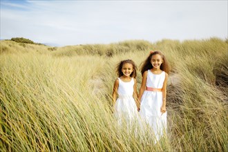 Mixed race sisters walking in grass