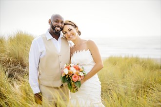 Newlywed couple smiling in grass