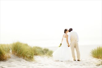 Newlywed couple kissing on beach