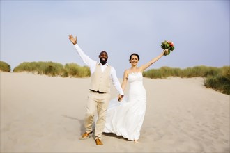 Newlywed couple cheering on beach