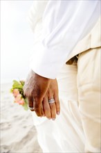 Newlywed couple holding hands on beach