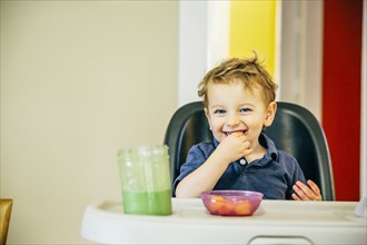 Caucasian boy eating in high chair