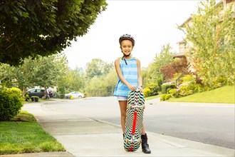 Mixed race girl riding skateboard on sidewalk