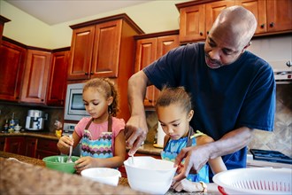 Father and daughters cooking in kitchen