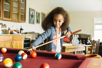 Mixed race girl playing pool